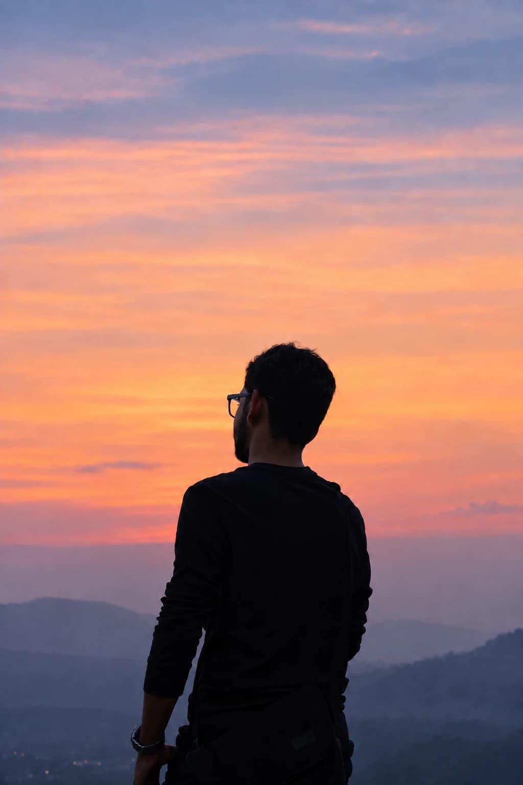 A sunset burning out over the hills outside Bengaluru, a figure in silhouette looking toward it.